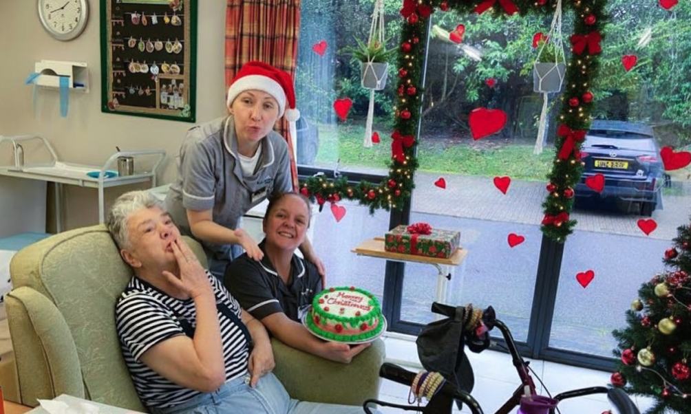resident with nurse sat with a christmas cake in the lounge